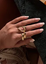 Set de dos anillos dorados de acero quirúrgico hipoalergénico. Uno es un anillo ancho con forma irregular y el otro es un anillo con forma de gota.