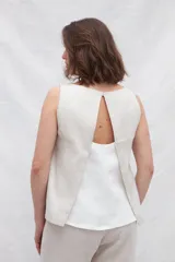 Musculosa de lino color blanco con paneles laterales en color beige, escote redondo y espalda con pliegues y cierre con botones.