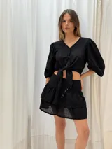 Minifalda negra con bordado inglés, cintura alta y detalle de argollas metálicas en el lateral.