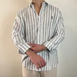 Camisa celeste y blanca a rayas verticales, de manga larga con puños abotonados y cuello clásico.