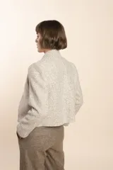 Chaqueta de sastrería color crudo con textura tweed, corte entallado, cuello mao y mangas largas.