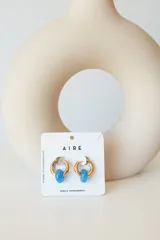 Aros de acero quirúrgico hipoalergénico con piedras naturales azules. Diseño de aro con dije circular colgante.