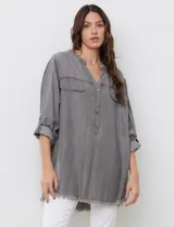 Blusa de tencel gris, con escote en V, abertura central con botones y bolsillos frontales.