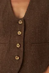 Chaleco marrón de lana con escote en V y cierre con botones.