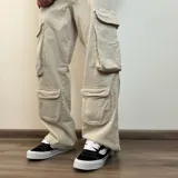 Pantalón jean color beige, de corte holgado y estilo cargo, con múltiples bolsillos laterales.