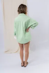 Camisa color crema de algodón liviano, calce oversize, con cuello camisero, cierre abotonado, mangas largas con opción de arremangado y dos bolsillos frontales con solapa.
