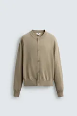 Cárdigan color beige de corte relaxed fit, tejido en hilatura con algodón y ramio. Tiene cuello redondo, manga larga, acabados en rib y cierre frontal de botonadura.