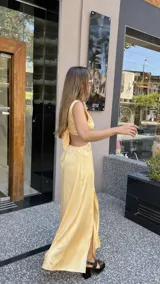 Vestido largo color durazno con escote pronunciado en V y aberturas laterales en la cintura. Presenta un drapeado frontal y falda con tajo lateral.