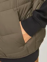 Chaleco acolchado verde militar sin mangas, con cuello alto, cierre frontal con cremallera y bolsillos delanteros.