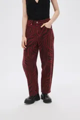 Pantalón de jean de tiro alto con estampado animal print de cebra en tonos borgoña y negro.