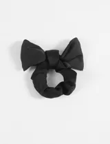 Gomita tipo scrunchie negra con moño incorporado, ideal para agregar un toque especial a peinados.
