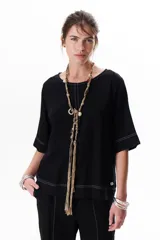 Blusa de lino color beige claro, con mangas 3/4 y cuello redondo. Presenta pespuntes a contratono en el centro, puños y ruedo.