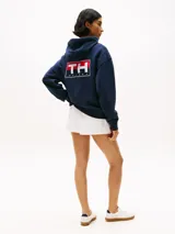 Buzo azul marino amplio con capucha y cordón distintivo, bolsillo canguro, puños y bajo de punto canalé, logo oversize de Tommy Hilfiger en la manga y la parte trasera, parche con logo de Tommy Hilfiger en el pecho y detalles distintivos de Hilfiger Sailing.