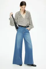 Blusa oversized con cuello elevado fruncido, abertura en V adelante y bajo recto. Mangas globo largas de corte raglán con abertura y botón en los puños.