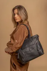 Cartera bandolera negra de símil cuero con textura granulada, doble asa rígida y correa de galón regulable. Presenta múltiples bolsillos frontales con cierre, un bolsillo con solapa y botón a presión, y dos divisiones internas.