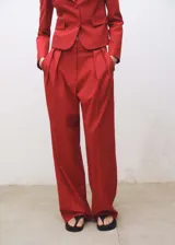 Pantalón de vestir rojo de corte wide leg, tiro alto, con detalle de pliegues, trabillas y forro interior.