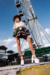 Mochila Sprayground negra con estampado a cuadros grises y blancos, diseño de boca de tiburón con dientes blancos y encías rojas.