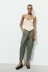 Pantalón capri color verde militar confeccionado en lino, de tiro medio, con bolsillos laterales y traseros. Cierre frontal con cremallera y botón.