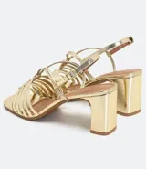 Sandalia de mujer color dorado metalizado, con taco grueso y punta cuadrada. Presenta un cabedal trenzado con tiras finas y tira ajustable con hebilla en el tobillo.