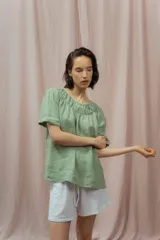 Blusa verde de lino con escote redondo fruncido y mangas cortas.