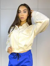 Campera blanca con textura capitonada, cuello camisero, cierre frontal con botones y puños elastizados.