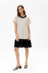 Vestido corto de algodón a rayas horizontales color beige, con cuello redondo negro y falda negra de lino.