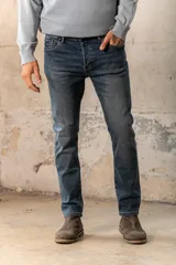 Pantalón de jean de corte recto, color azul medio, con bolsillos delanteros y traseros.