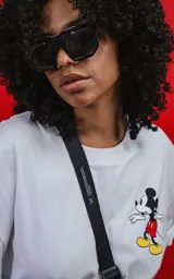 Remera oversize de algodón premium color blanco, con cuello redondo y manga corta. Presenta un pequeño estampado del personaje Mickey Mouse en el lado izquierdo del pecho.