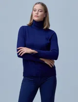 Polera de punto fino marca Nienty, color blanco, con cuello alto volcado y mangas largas con detalle de tajo en los puños.