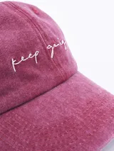 Gorro de gabardina color rosado con visera y bordado frontal con la frase "Keep Going".