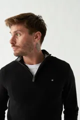 Sweater de punto negro con cuello alto y cierre parcial con cremallera.