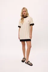 Vestido de tejido de punto color amarillo con rayas verticales en tono más claro. Presenta cuello redondo y puños en color celeste con terminación de pespunte en color naranja. Lleva un bordado de iniciales en el pecho.