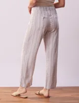 Pantalón largo de lino y rayón a rayas verticales grises y blancas. Tiene pretina elastizada con lazo de ajuste, bolsillos delanteros y traseros.