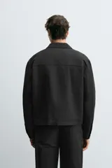 Sobrecamisa negra relaxed fit confeccionada en tejido con algodón, lino y lyocell. Cuello solapa y manga larga acabada en puño con botón. Bolsillos plastrón con solapa en pecho y laterales en cadera. Cierre frontal de botonadura.