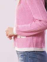 Cardigan de punto color beige con textura tipo tweed, escote redondo, cierre frontal con botones dorados y bolsillos simulados.