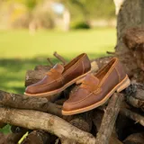 Mocasín de cuero vacuno color marrón, con detalle de antifaz en gamuza. Tiene taco de madera foliado en cuero de 2,5cm y entre suela de goma de 1cm.