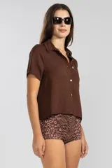 Camisa marrón de lino y Tencel, de manga corta, con cuello camisero y cierre abotonado al frente.