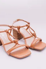 Sandalias de tacón color naranja, con puntera cuadrada, tiras finas con detalle de nudos y tacón geométrico de madera.