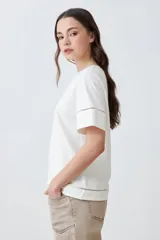 Remera blanca de manga corta con cuello redondo y detalle de vainillas en cuello, mangas y centro.
