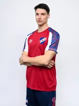 Remera de entrenamiento azul marino con detalles en blanco y rojo en los hombros y mangas. Incluye el logo de Umbro y el escudo del Club Nacional de Football en el pecho.