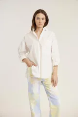 Camisa blanca de mangas largas con puños abotonados, cuello clásico y bolsillo en el pecho.