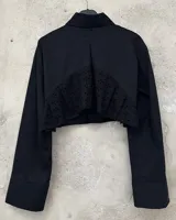 Camisa negra de algodón, corte crop, con cuello clásico, cierre frontal con botones y mangas largas con puños abotonados. Estampado con la palabra "Fragilità" en color blanco en el frente y en la manga izquierda.