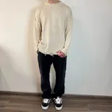 Sweater tejido color crudo, de corte holgado, con cuello redondo y terminaciones rotas en puños y ruedo.