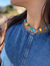 Collar corto con piedras turquesas irregulares, cuentas de cerámica amarillas y verdes, y cuentas plásticas naranjas y azules.