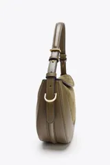 Bolso bandolera ovalado color verde oliva, con solapa de gamuza y asa de cuero ajustable.