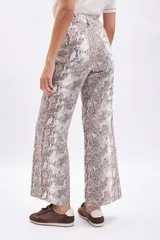 Pantalón de tiro alto, corte ancho y largo, con estampado de piel de serpiente en tonos beige y marrón. Presenta costuras visibles en color marrón oscuro.