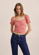 Top corto a cuadros rojos y blancos, con escote cuadrado, mangas cortas abullonadas y fruncido en el centro.