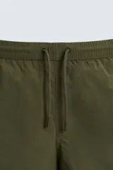 Bañador corto color verde militar confeccionado en tejido técnico. Cuenta con cintura elástica ajustable con cordón, bolsillos laterales, bolsillo trasero de vivo y forro interior.