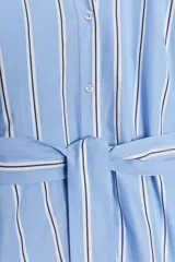 Vestido midi de algodón a rayas celestes y blancas con cinturón de la misma tela, cuello redondo, manga abullonada con puño y cierre frontal con botones.