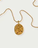 Collar dorado con dije ovalado texturizado con incrustaciones de circonitas en forma de luna creciente, ojo turco y estrellas de diferentes tamaños.